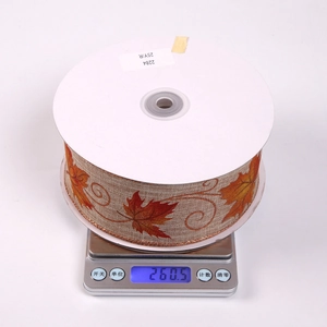 Detail of autumn maple leaf ribbon with metallic edges on a spool showing material texture