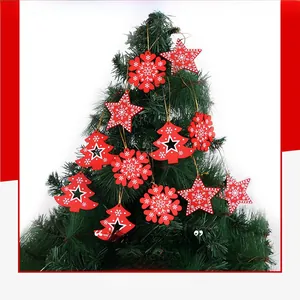 Close-up of red and white wooden snowflake and star ornaments hanging on a green Christmas tree