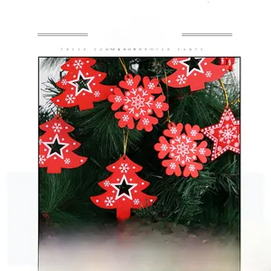 Detail of red wooden Christmas snowflake and star ornaments hanging on green pine branches