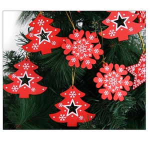 Detail of red wooden snowflake and star ornaments hanging on a green Christmas tree branch