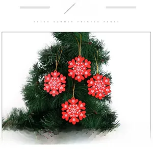 Close-up of four red wooden snowflake ornaments with white patterns on a Christmas tree