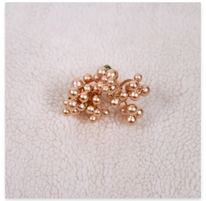 Macro shot of rose gold berry cluster earrings on soft white textured background