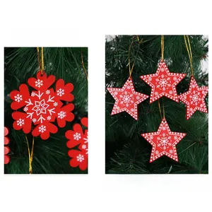 Detail of red wooden Christmas snowflake and star ornaments hanging on a green tree branch
