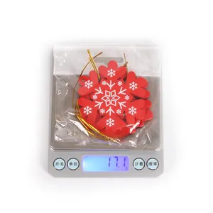 Detailed view of red wooden snowflake ornaments with gold hanging cords on a digital scale