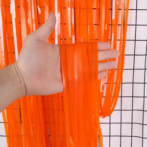 Detail of bright orange foil fringe curtain for party backdrops with shiny metallic texture