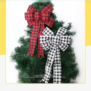 Close-up of red and black buffalo plaid fabric bows hanging on a green Christmas tree