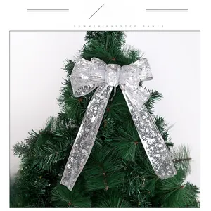 Close-up of a silver Christmas ribbon bow with snowflake patterns on a tree branch