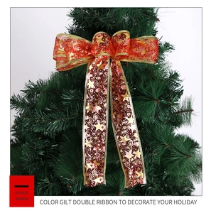Detail of red double-layered Christmas ribbon with gold stars and notes on a tree