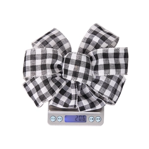 Detail shot showing 20.6g weight of black and white plaid Christmas bow on a digital scale