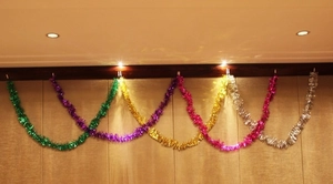 Close-up of 2m multi-colored Christmas tinsel garlands hanging on a rustic wooden beam