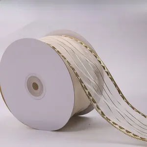 Close-up of cream sheer organza ribbon with metallic gold wire edges on a white spool