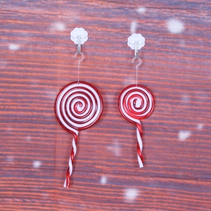Set of two red and white spiral lollipop Christmas tree ornaments on wood background