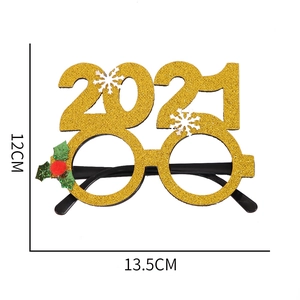 Close-up of golden glitter 2021 holiday glasses with snowflake and holly leaf decorations