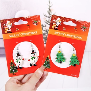 Weihnachts-Ohrhänger mit Schneemann und grünem Tannenbaum auf festlicher Schmuckkarte