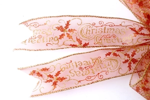 Detail of sheer pink Christmas ribbon with gold glitter Christmas Greeting lettering