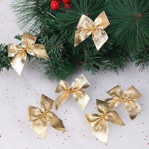 Macro shot of gold glitter Christmas bows set against snow background and pine branches