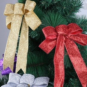 Nahaufnahme glitzernder Weihnachtsschleifen in Gold und Rot an grünen Tannen zweigen