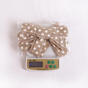Detailed view of burlap Christmas bow with white polka dots on a digital scale