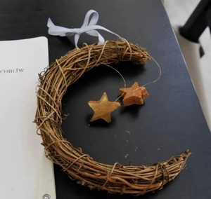 Detail of moon-shaped wooden rattan wreath with star pendants and white ribbon bow