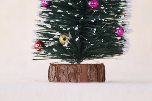 Detailansicht eines Mini-Weihnachtsbaums mit Flockschnee und bunten Ornamenten