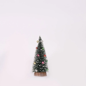 Nahaufnahme eines Mini-Weihnachtsbaums mit Schneespitzen, bunten Kugeln und Holzsockel