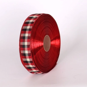 Macro detail of red metallic Christmas ribbon featuring classic red and black tartan borders