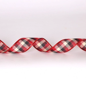 Close-up of red and black tartan Christmas ribbon with shiny metallic edges for DIY crafts