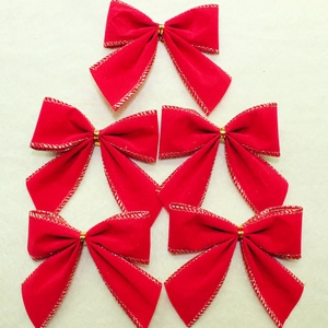 Five red velvet Christmas bows with gold edges arranged on a textured background