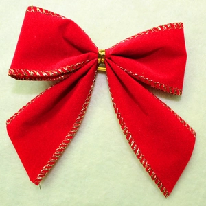 Close-up of red velvet Christmas bow with gold metallic edges for festive holiday decoration