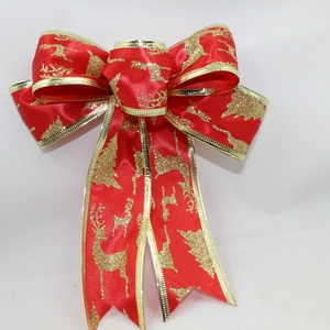 Detail of red velvet Christmas bow with gold edges and festive glitter reindeer patterns