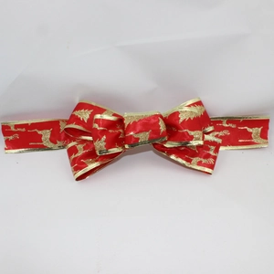 Detailed macro shot of red velvet Christmas bow with gold reindeer and tree patterns