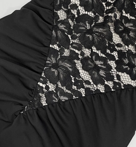 Détail de la dentelle florale et des coutures plissées sur une robe noire sans manches