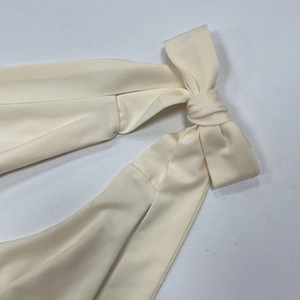 Detaillierte Makroaufnahme des cremefarbenen Rippstoffs und des Schleifendesigns am Top