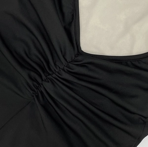 Détail de l'encolure froncée sur une robe noire sans manches avec patchwork en dentelle