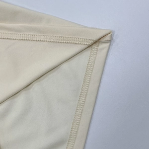 Detailaufnahme von cremfarbenem Textil mit präziser Doppelnaht und feiner Rippstruktur
