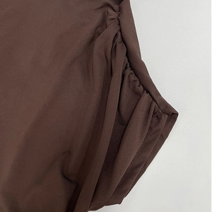 Détail de près du tissu tricoté élastique marron avec côté froncé et drapé fluide