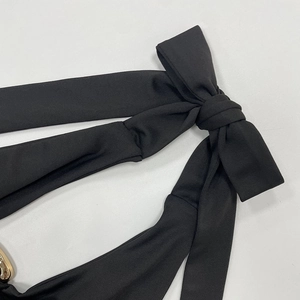 Detaillierte Makroansicht des schwarzen Neckholder-Trägers mit Schleife und Goldring