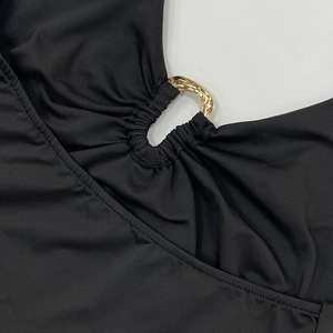 Detail aus schwarzem Faltenstoff mit polierter goldener Metallschnalle auf weißem Grund