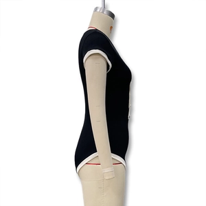 Détail d'un body noir moulant avec passepoil blanc contrasté et fermeture boutonnée