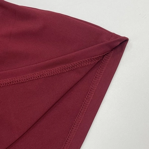 Nahaufnahme der Overlock-Naht am Saum des weinroten, gestrickten Oberteils