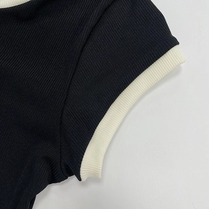 Détail de maille côtelée noire avec liseré blanc contrasté sur la manche et le col