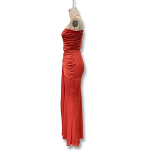 Detail of coral orange ruched maxi dress showing side pleats and stretch fabric texture