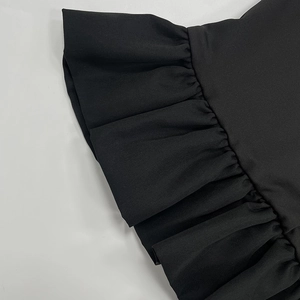 Détail rapproché de l'ourlet à volants et de la texture du tissu noir de ce haut chic