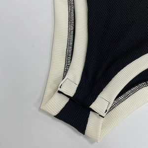 Gros plan détaillé du tissu noir côtelé avec coutures contrastées et bordure blanc crème