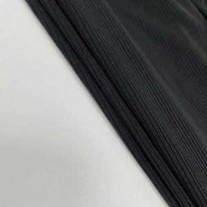 Gros plan sur la texture du tissu en maille côtelée noire pour combinaison moulante sexy