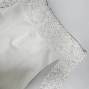 Détail de l'encolure en dentelle florale blanche et texture du tissu sur la robe
