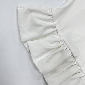 Vue détaillée du haut blanc sans manches montrant l'ourlet à volants et les coutures