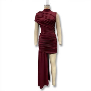 Detail of burgundy sleeveless dress featuring dense ruching and asymmetric draped hemline