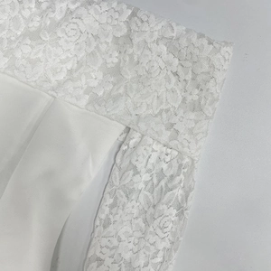 Gros plan sur la dentelle florale complexe de la robe d'été blanche à épaules dénudées