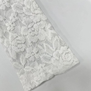 Détail de la broderie florale en dentelle blanche avec roses sur la manche de robe